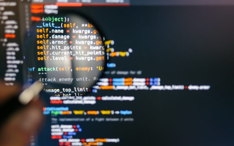 Program code on computer display in magnifying glass. Close-up Program code on computer display in magnifying glass. Close-up